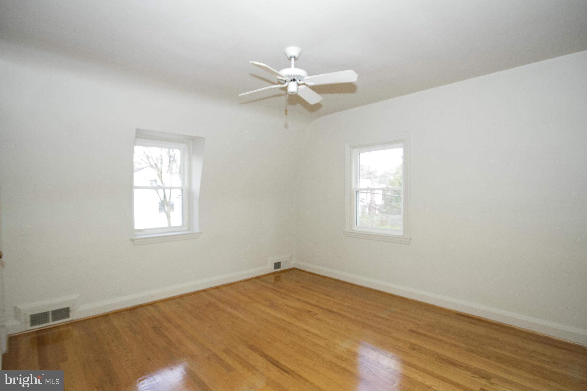 2504 Wetherburn Road Baltimore, MD 21209 - Photo 9 of 17 an empty room with wooden floor fan and windows