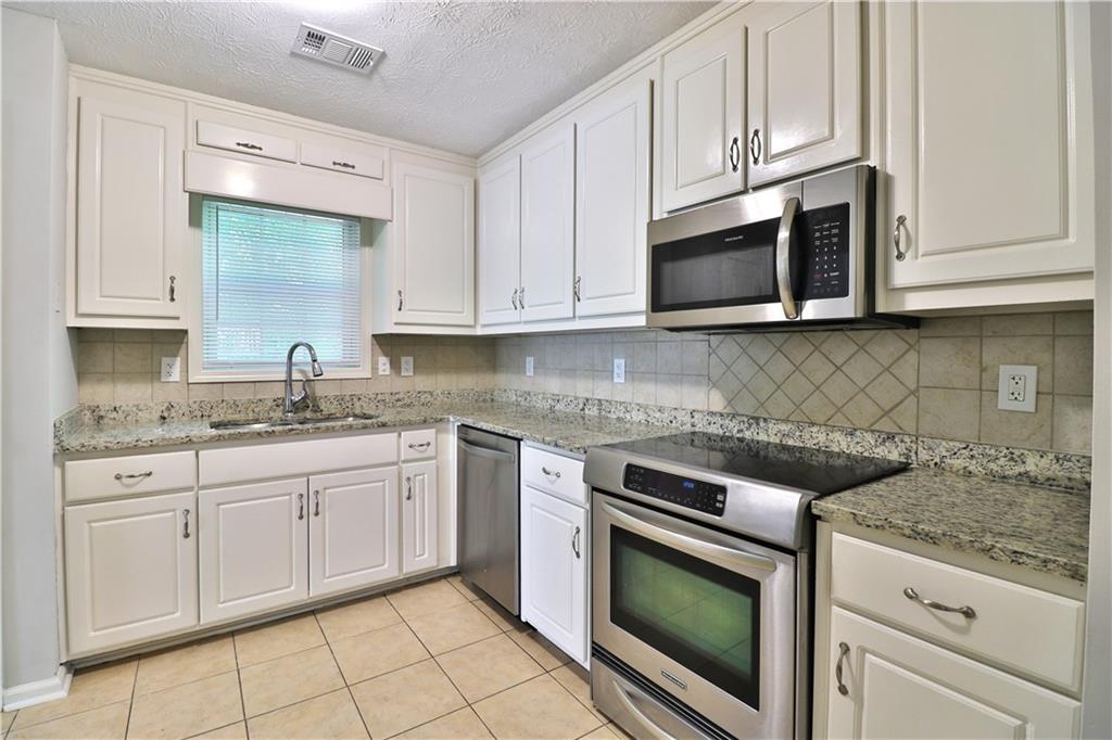 353 Fall View Court Winder, GA 30680 - Photo 26 of 61 a kitchen with granite countertop white cabinets stainless steel appliances and a sink