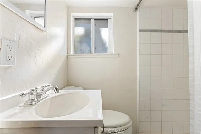 a bathroom with a sink a toilet and shower