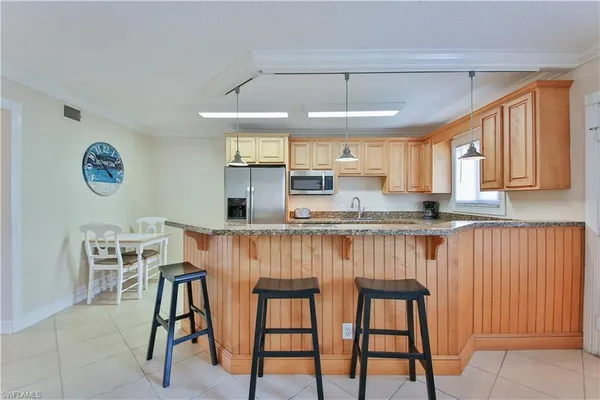 a kitchen with stainless steel appliances granite countertop a table chairs sink and cabinets