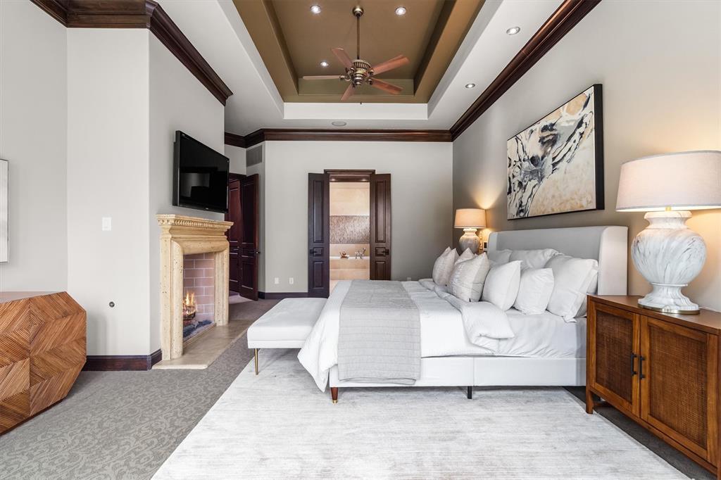 9 Victory Lane Double Oak, TX 75077 - Photo 18 of 40 The primary suite offers a peaceful retreat with warm architectural details and views of the surrounding trees. Generous space allows for a comfortable sitting area and relaxing evenings by the fireplace.