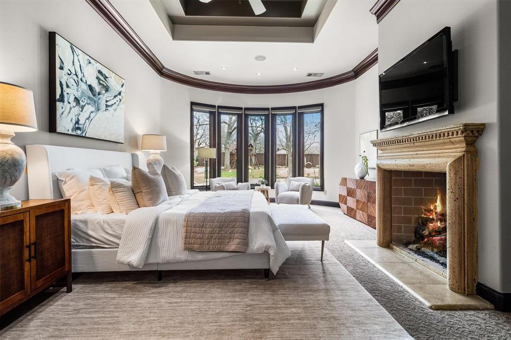 9 Victory Lane Double Oak, TX 75077 - Photo 19 of 40 Another view of the primary suite highlights its impressive scale, elegant ceiling details, and natural light. A fireplace adds warmth and ambiance to this private retreat.