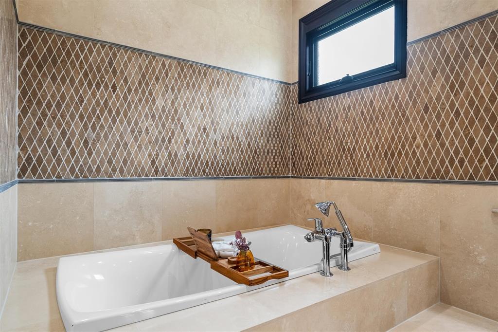9 Victory Lane Double Oak, TX 75077 - Photo 21 of 40 Relax and unwind in the soaking tub surrounded by warm stone finishes and natural light. A calming space designed to feel like a private spa.