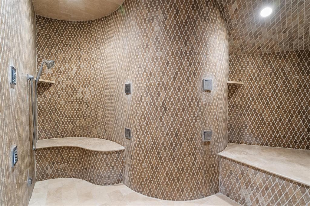 9 Victory Lane Double Oak, TX 75077 - Photo 23 of 40 Oversized walk-in shower featuring beautiful stonework, dual shower areas, and built-in seating. A luxurious feature of the primary bath designed for comfort and relaxation.