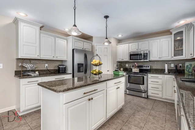 a kitchen with stainless steel appliances granite countertop a sink a stove a refrigerator a center island a stove and cabinets