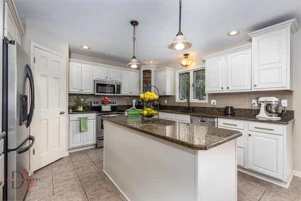 a kitchen with stainless steel appliances granite countertop a sink a stove a refrigerator and cabinets