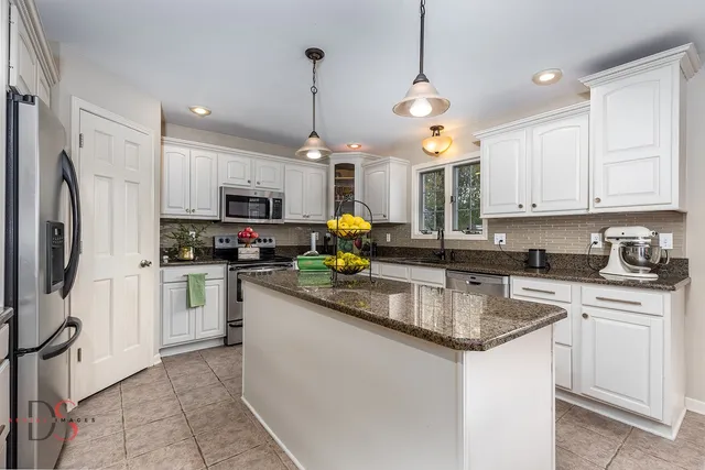 a kitchen with stainless steel appliances granite countertop a sink a stove a refrigerator and cabinets