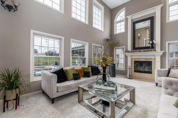 a living room with furniture a fireplace a potted plant and a large window