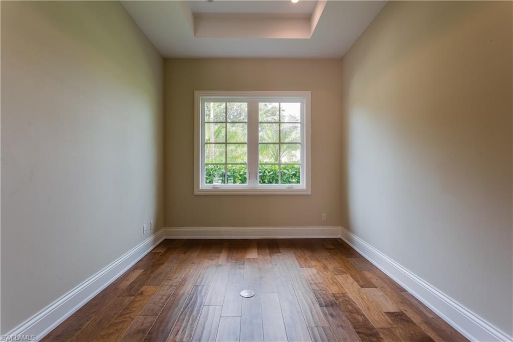 6578 Ridgewood Drive Naples, FL 34108 - Photo 12 of 35 an empty room with wooden floor and windows