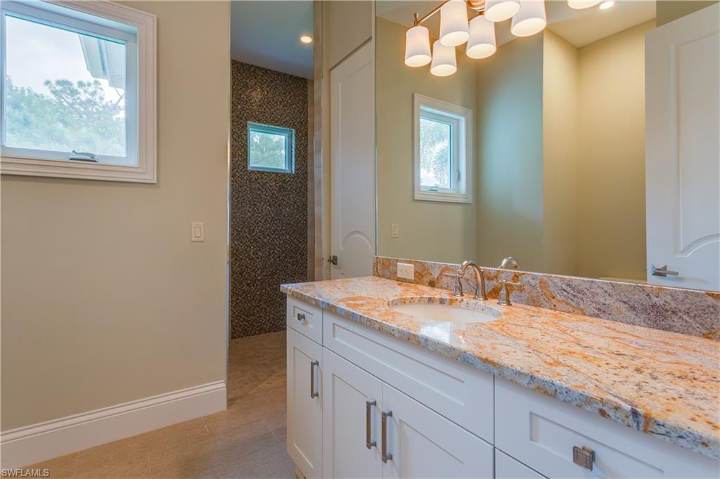 6578 Ridgewood Drive Naples, FL 34108 - Photo 22 of 35 a bathroom with a granite countertop sink and a mirror