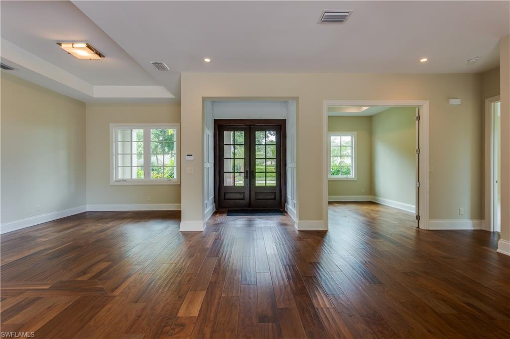 6578 Ridgewood Drive Naples, FL 34108 - Photo 9 of 35 an empty room with wooden floor and windows