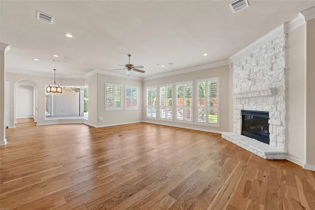 a view of an empty room with wooden floor and a fireplace