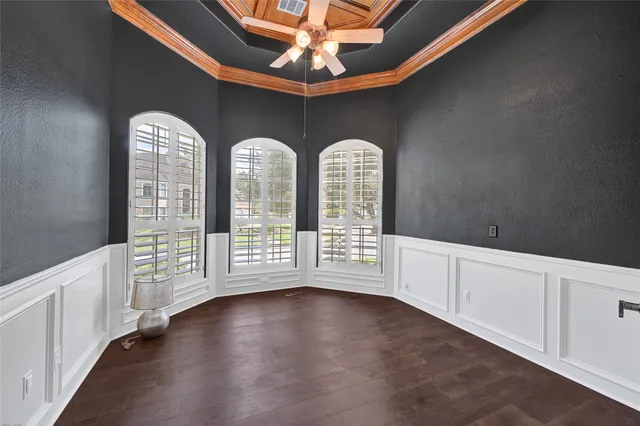 a view of an empty room with chandelier fan and wooden floor