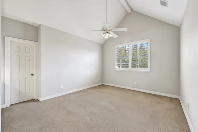 an empty room with chandelier fan and windows
