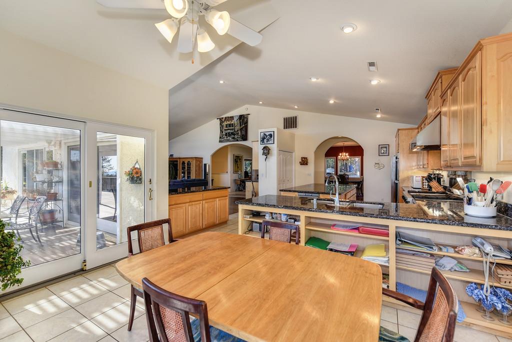 24200 Golden Ridge Drive Volcano, CA 95689 - Photo 18 of 58 a large kitchen with stainless steel appliances a stove a refrigerator a sink dishwasher a dining table and chairs with wooden floor