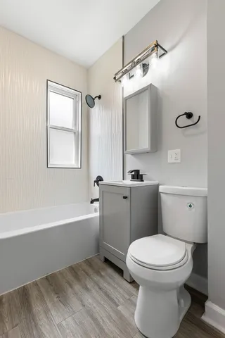 a bathroom with a toilet a sink a mirror a bathtub and vanity