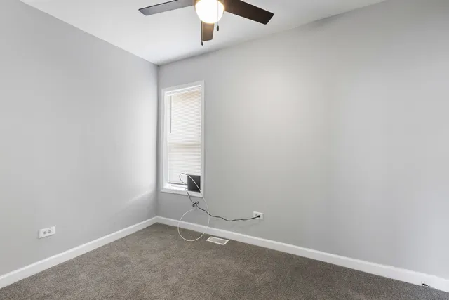 an empty room with a ceiling fan and window