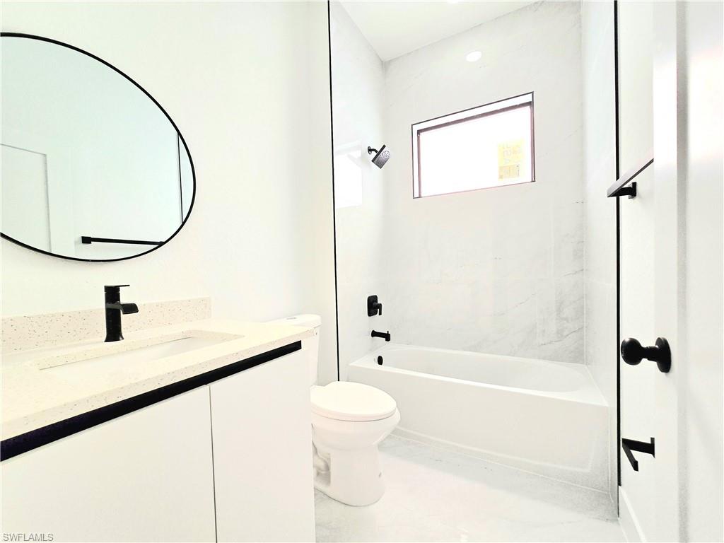 2522 Alice Place Lehigh Acres, FL 33971 - Photo 24 of 34 a bathroom with a granite countertop sink a toilet and a mirror