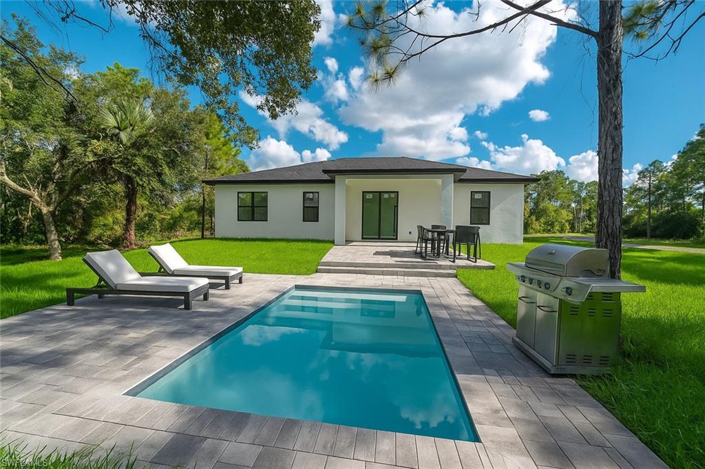 2522 Alice Place Lehigh Acres, FL 33971 - Photo 31 of 34 a view of a house with a yard patio and fire pit