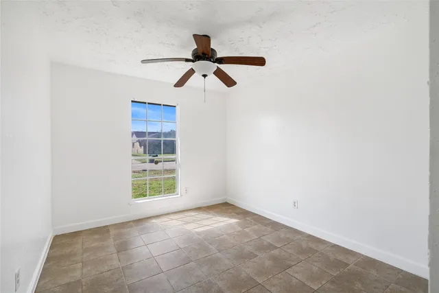 a view of empty room with windows and ceiling fan