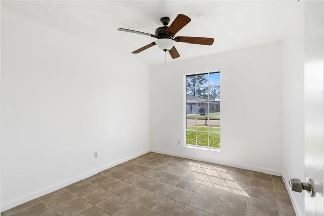 an empty room with a ceiling fan and carpet