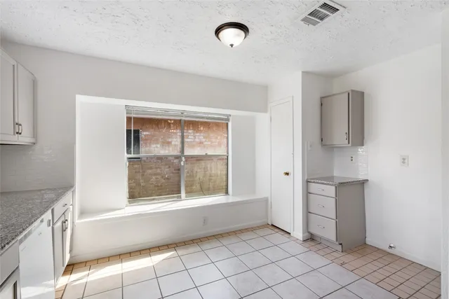 a view of an empty room with window and cabinet
