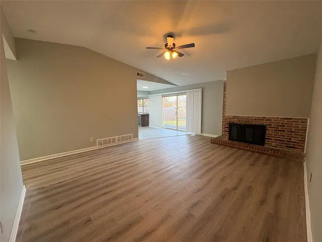 a view of an empty room with wooden floor and a fireplace