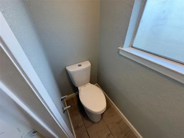 a white toilet sitting next to a small window