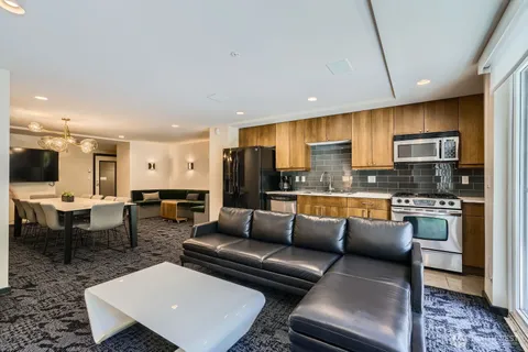 a living room with stainless steel appliances furniture and a kitchen view