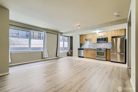 a view of kitchen with stainless steel appliances wooden floor and window