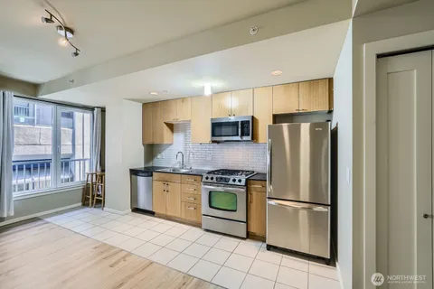 a kitchen with stainless steel appliances granite countertop a refrigerator a stove top oven a sink and dishwasher