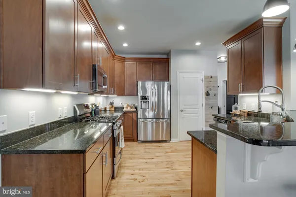a kitchen with stainless steel appliances granite countertop a stove top oven a sink a counter space and cabinets