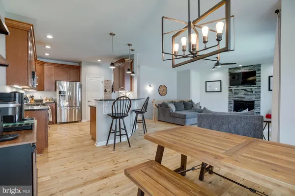 a kitchen with stainless steel appliances granite countertop a kitchen island hardwood floor sink stove dining table and chairs