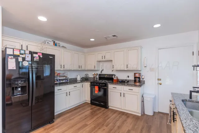 a kitchen with stainless steel appliances a sink cabinets and wooden floor