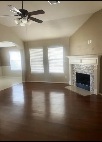an empty room with wooden floor fireplace and windows