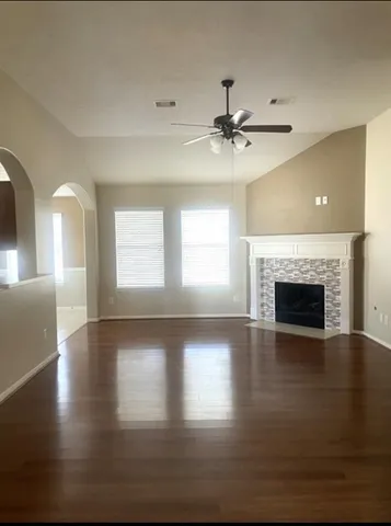 a view of an empty room with wooden floor fireplace and a window