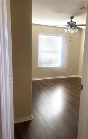 an empty room with wooden floor fan and windows