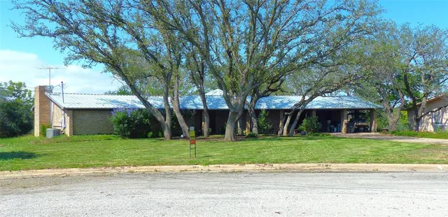 a front view of a house with a garden and trees