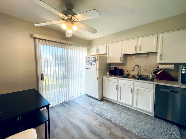a kitchen with a refrigerator a stove cabinets and wooden floor