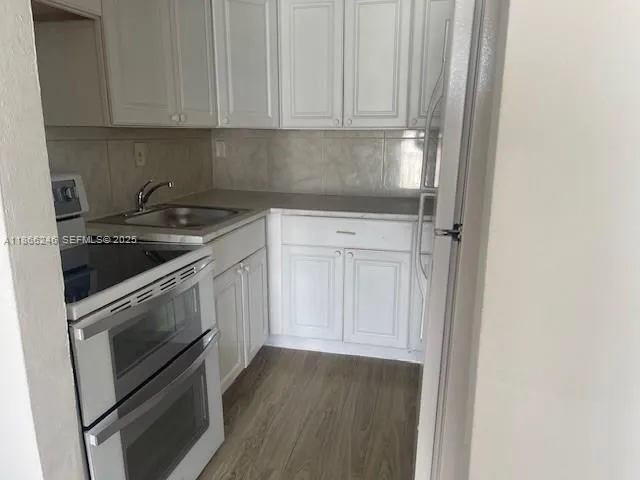 a kitchen with granite countertop white cabinets and stainless steel appliances