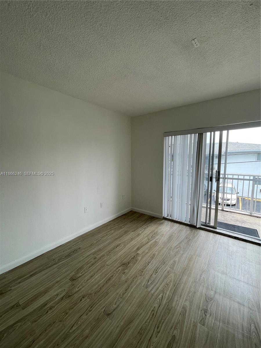 1735 Northeast 164th Street, Unit F204 North Miami Beach, FL 33162 - Photo 5 of 25 a view of an empty room with wooden floor and a window
