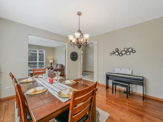 a kitchen with stainless steel appliances kitchen island granite countertop a stove top oven a sink dishwasher a dining table and chairs with wooden floor