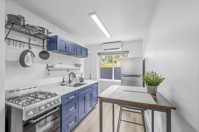 a kitchen with kitchen island cabinets a stove a sink and a table with wooden floor
