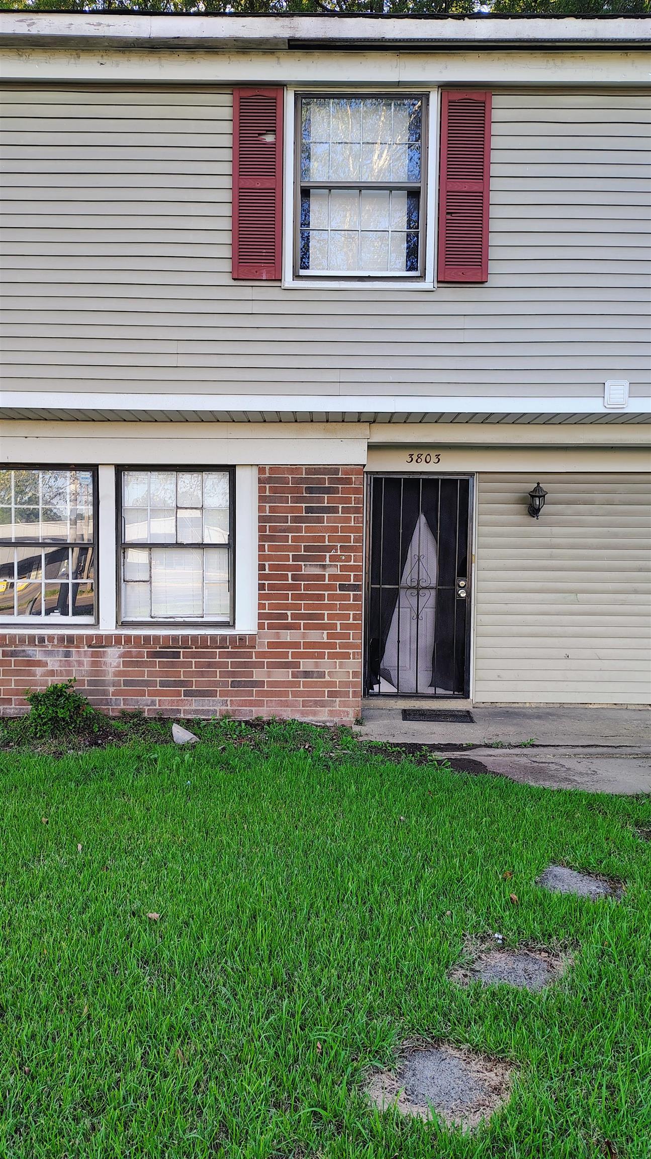 Doorway to property featuring a yard and brick siding