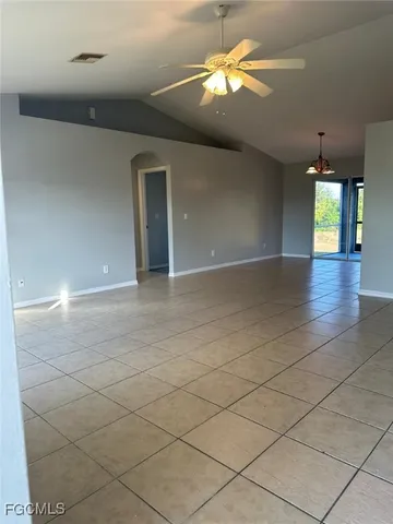 an empty room with chandelier fan and windows