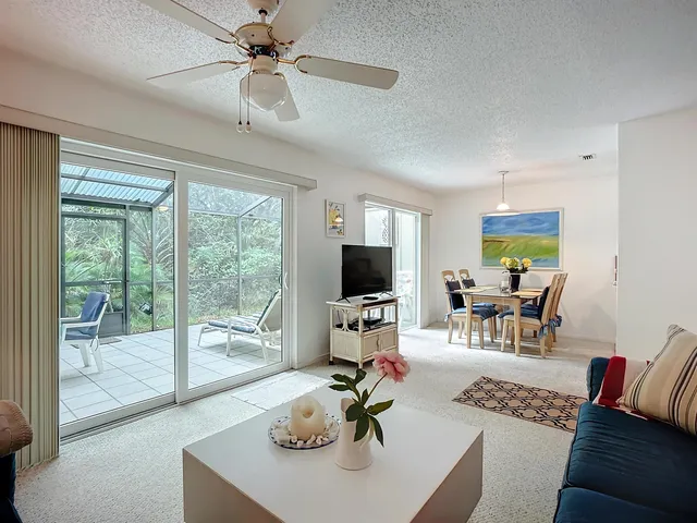 a living room with furniture a flat screen tv and a floor to ceiling window