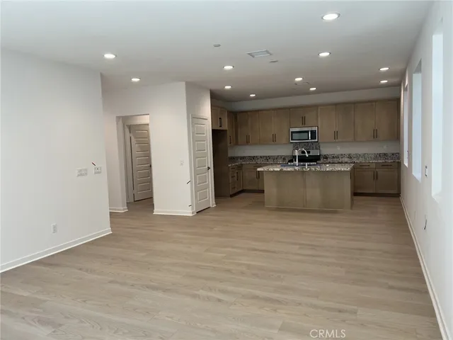 a large kitchen with stainless steel appliances a large counter top a stove a refrigerator and a sink