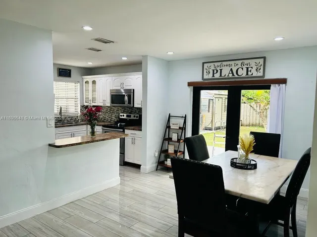 a view of a dining room with furniture a kitchen and chandelier