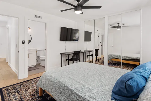 a bedroom with a bed a flat screen tv and a dresser