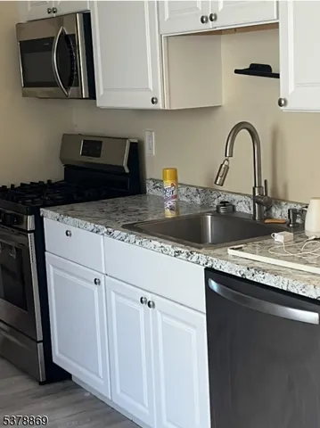 a kitchen with granite countertop a sink a stove and cabinets
